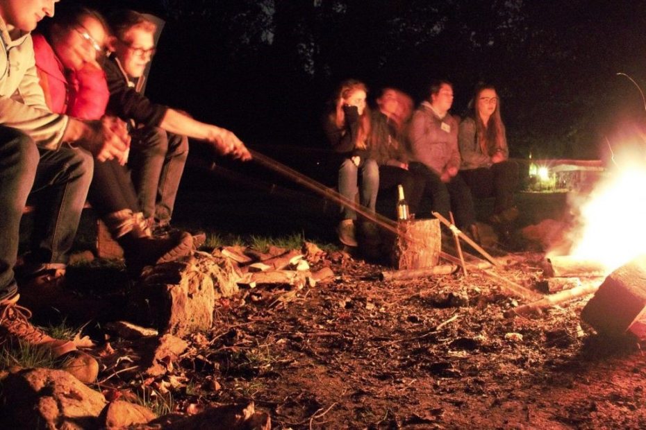 Eine Gruppe Menschen sitzt am Lagerfeuer
