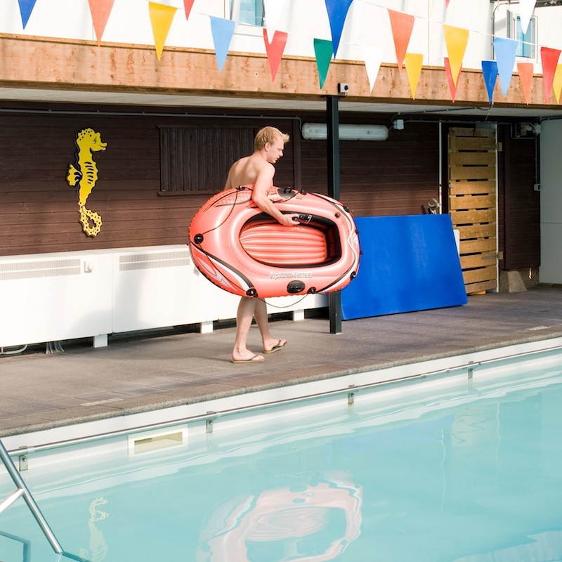 Foto von Indoor Pool mit Junge mit aufblasbarem Boot am Beckenrand