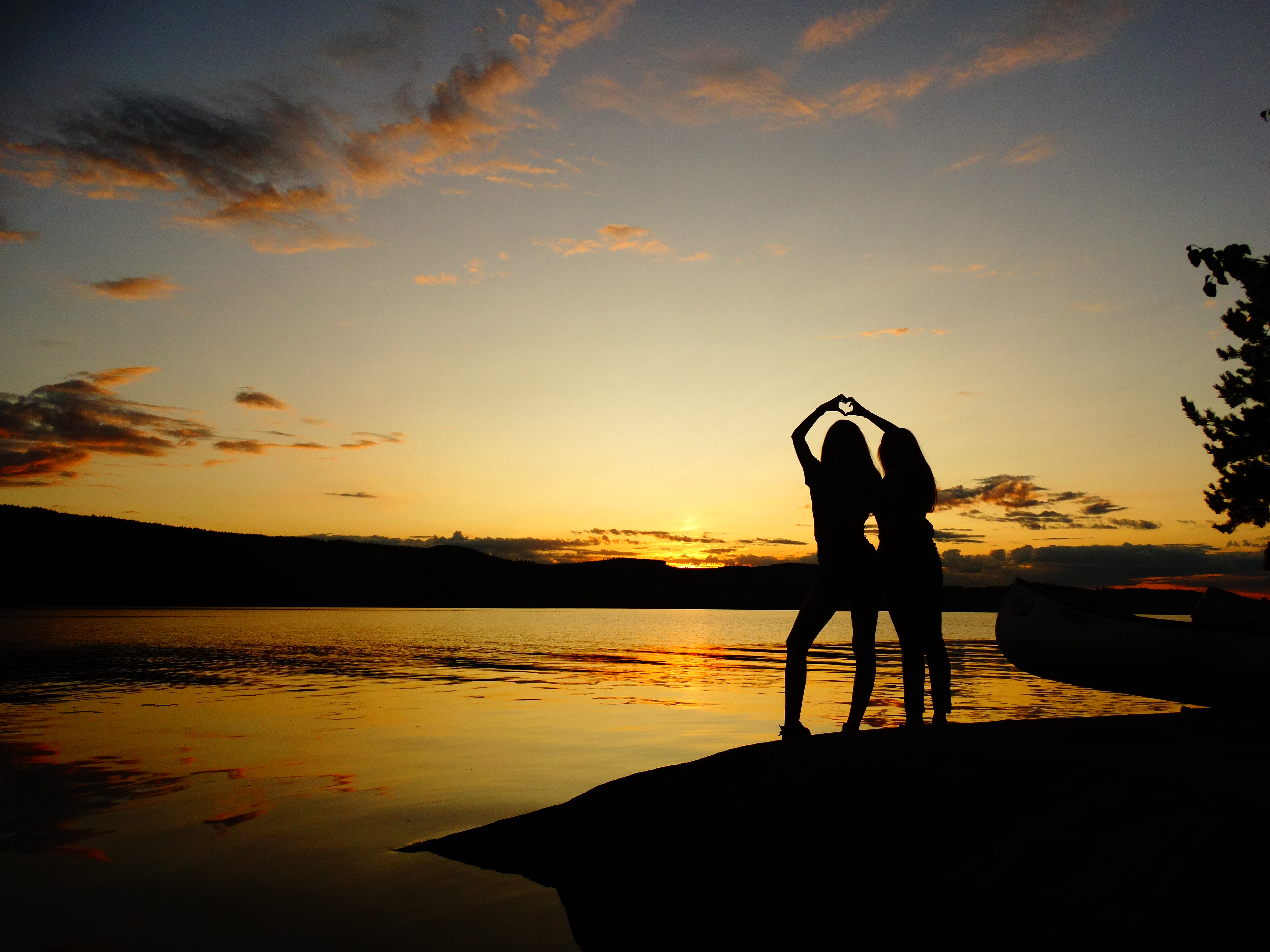 Zwei Mädchen stehen bei Sonnenuntergang am See